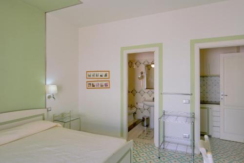 a white bedroom with a bed and a bathroom at Hotel Residence Mendolita in Lipari