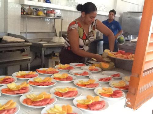 a woman preparing food in a kitchen with plates of food at Casa de las Olas Surf & Beach Club in Acapulco
