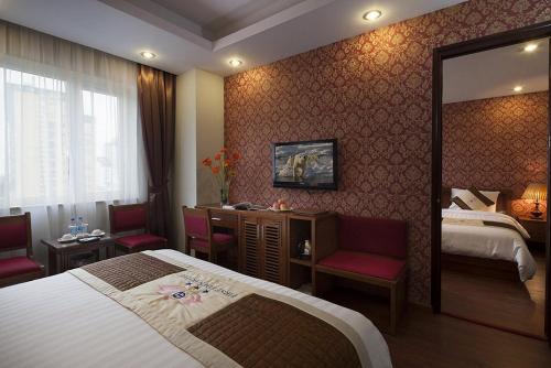 a hotel room with a bed and chairs and a mirror at First Eden Hotel - Hang Bun in Hanoi