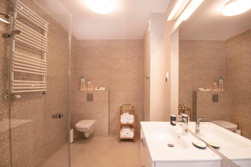 a bathroom with a sink and a shower and a toilet at LATO apartament Polanki Park z miejscem parkingowym in Kołobrzeg