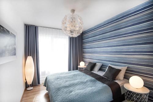 a bedroom with a blue striped wall with a bed at LATO apartament Polanki Park z miejscem parkingowym in Kołobrzeg
