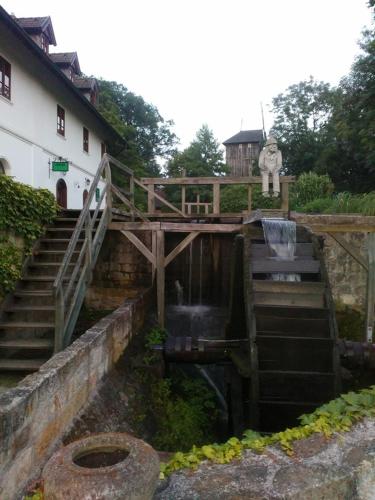 a wooden bridge over a waterfall next to a building at Bučický mlýn in Rožďalovice