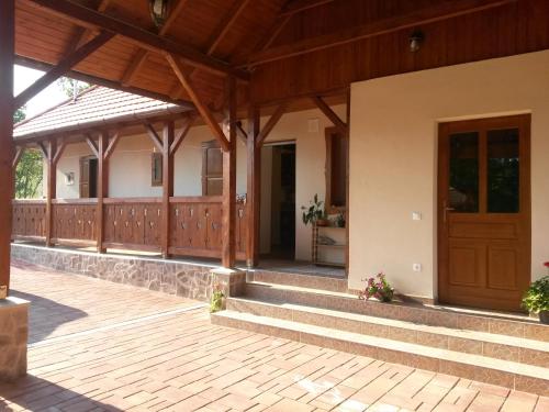 a house with a porch and a wooden door at Martonyi Erdőszéli Vendégház in Martonyi