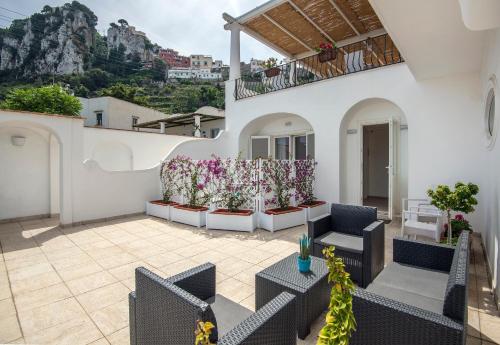 a patio with chairs and tables with a mountain in the background at Villa Patrizi in Capri