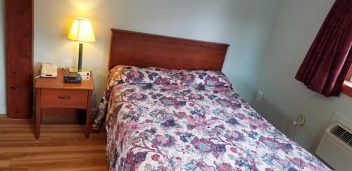 a bedroom with a bed and a night stand with a phone at Wolds Motel - Mt. Pleasant in Mount Pleasant