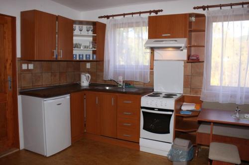 cocina con armarios de madera y horno de fogón blanco en Chaty u Toma Slapy en Nalžovice