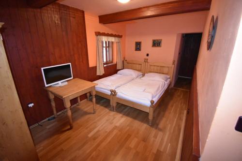 a small bedroom with a bed and a desk with a computer at Horská bouda U Kokrháče in Dolní Malá Úpa