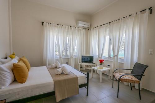 a bedroom with a bed and a chair and windows at Skouros Villa in Kastrí