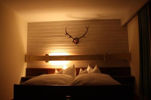 Una cama con una cabecera con un cuerno. en DEVA Hotel-Restaurant Fischerwirt inklusive Chiemgau Card en Ruhpolding