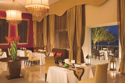 a restaurant with tables and chairs and a chandelier at Dreams Jade Resort & Spa - All Inclusive in Puerto Morelos