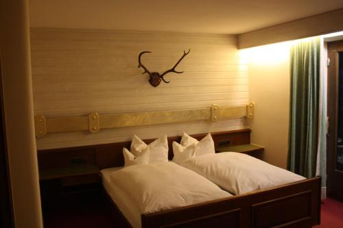 a bedroom with a bed with a antler on the wall at DEVA Hotel-Restaurant Fischerwirt inklusive Chiemgau Card in Ruhpolding