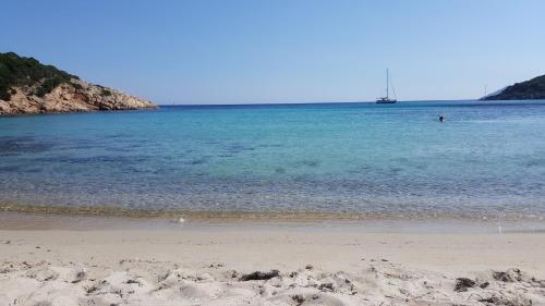 a beach with the ocean and a boat in the water at Vacanze Mare Teulada in Teulada