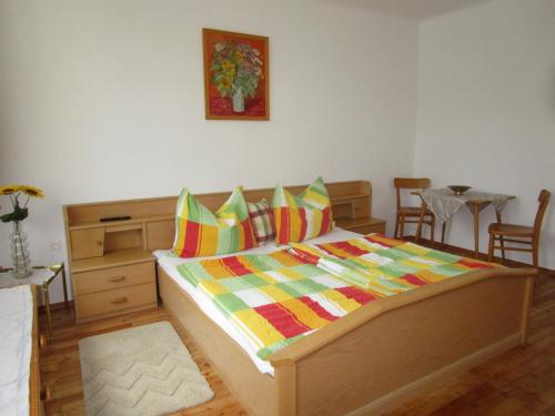 a bedroom with a large wooden bed with colorful pillows at Dorfwirtshaus Rauch in Eschabruck