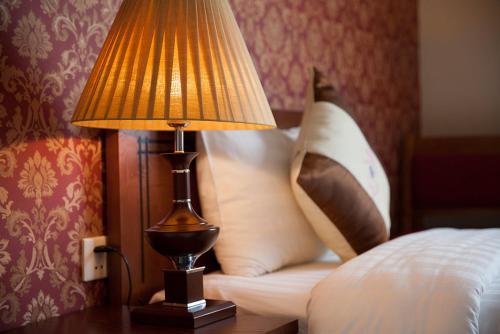 a lamp sitting on a table next to a bed at First Eden Hotel - Hang Bun in Hanoi