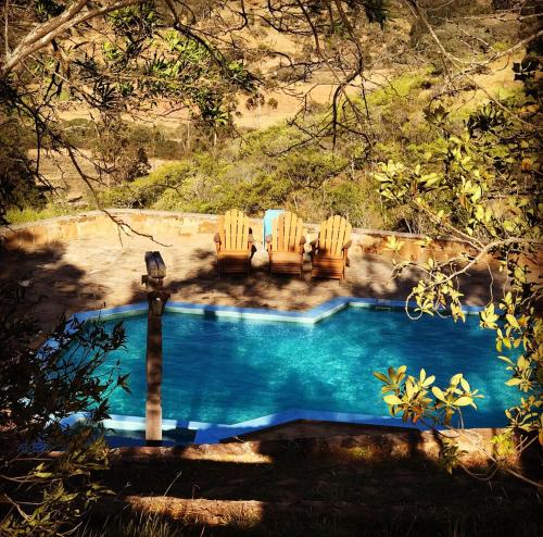 a swimming pool with two chairs and a table at El Pueblito Hotel Boutique in Samaipata