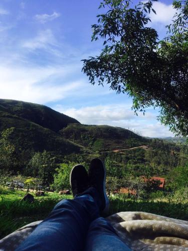 a man laying on the grass with his feet on a hill at El Pueblito Hotel Boutique in Samaipata
