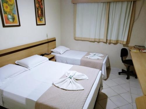 a hotel room with two beds and a chair at Hotel Marfim I in Sumaré