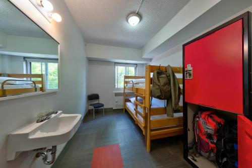 HI Edmonton - Hostel في إيدمونتون: حمام مع حوض ومرآة وأسرّة بطابقين