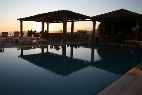 a swimming pool with a sunset in the background at Apartments Grand in Sveti Stefan