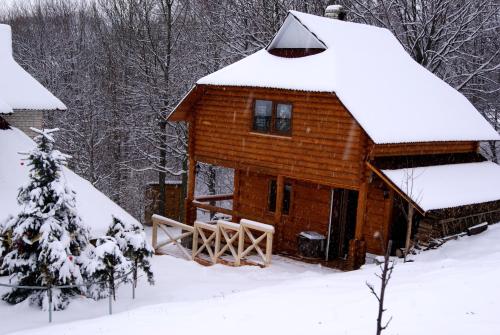 a log cabin with snow on the roof at Rakhiv Plai in Rakhiv