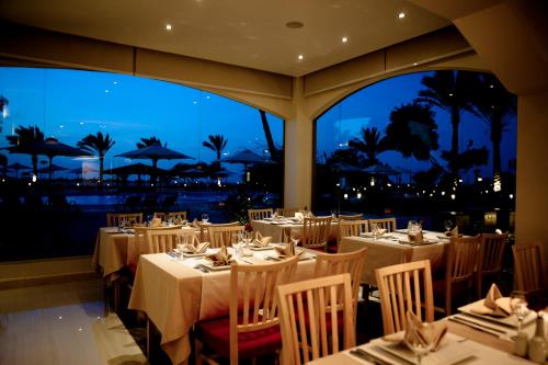 - un restaurant avec des tables et des chaises offrant une vue sur l'océan dans l'établissement Mousa Coast Hotel & Spa, à Ras Sudr