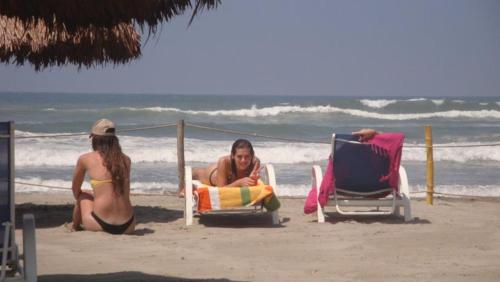 two women sitting in lawn chairs on the beach at Casa de las Olas Surf & Beach Club in Acapulco