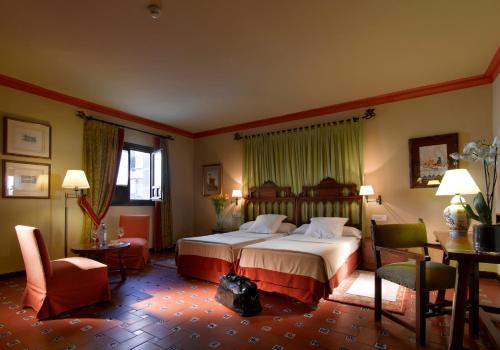 a hotel room with a bed and a table and chairs at Parador de Ubeda in Úbeda