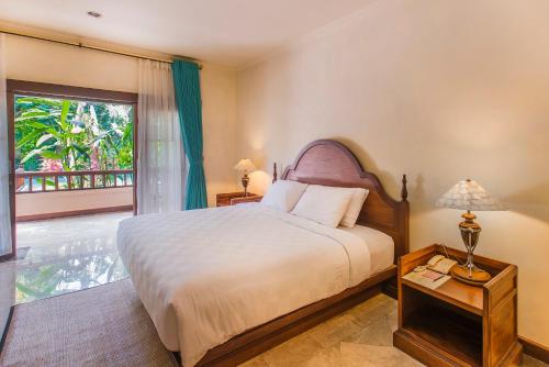 a bedroom with a bed and a large window at Samhita Garden Ubud in Ubud