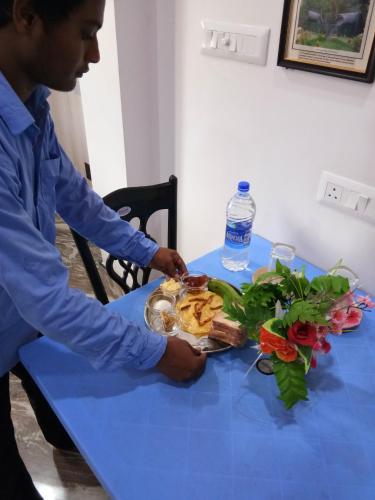 a man sitting at a blue table with a plate of food at Asian Grand Villa in Bolpur