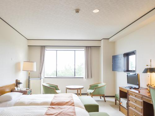 a hotel room with a bed and a desk and a television at Oarai Park Hotel in Oarai