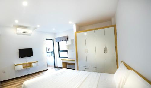 ein weißes Schlafzimmer mit einem Bett und einem TV in der Unterkunft Era Apartment Nguyen Van Huyen in Hanoi