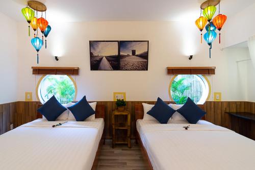 two beds in a room with two windows at An Bang beach Happy Village in Hoi An