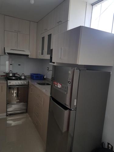a kitchen with white cabinets and a stainless steel refrigerator at Nino´s Residence Departamentos VIP Amoblados in Tacna