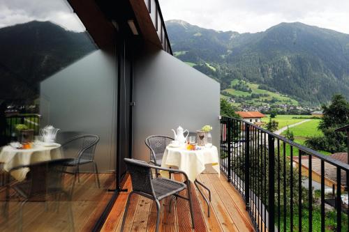 a balcony with tables and chairs and a view of mountains at derNeuwirt in Schwendau