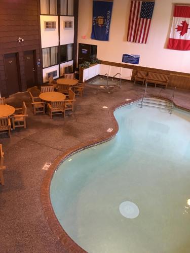 a large swimming pool in a room with tables and chairs at Superior Inn in Superior