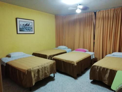 a room with three beds in a room at Hospedaje Oasis in Chiclayo