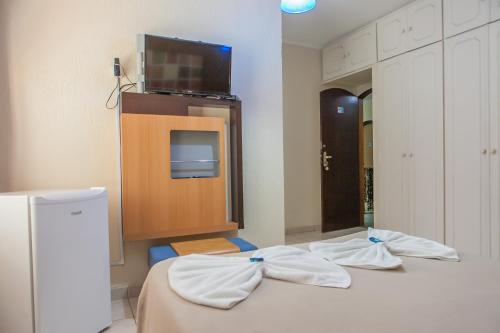 um quarto com duas camas e uma televisão na parede em Pousada da Costa em Caraguatatuba