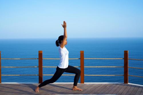 a woman doing a yoga pose by the ocean at Six Senses Uluwatu in Uluwatu