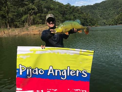 a man holding a fish on a sign in the water at Ecohotel Campo Alegre Norcasia Caldas in Norcasia