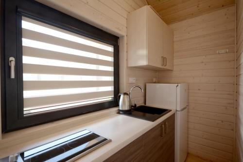 a kitchen with a window and a sink and a refrigerator at Bursztynowo Domki Letniskowe in Ostrowo