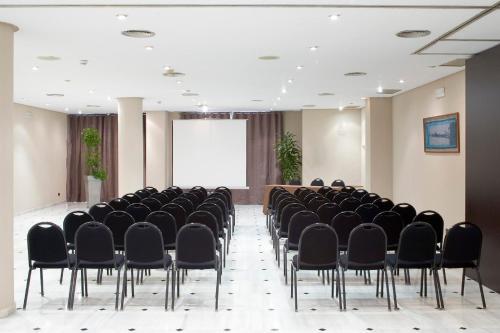 a conference room with black chairs and a screen at URH Ciutat de Mataró in Mataró