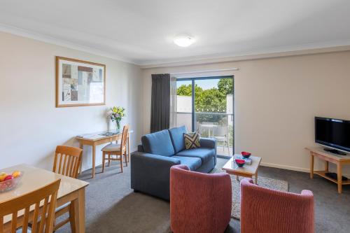 sala de estar con sofá azul y mesa en Nesuto Mounts Bay, en Perth