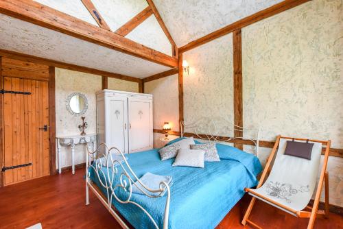 a bedroom with a blue bed and two chairs at Laukdvaris in Laukžemė