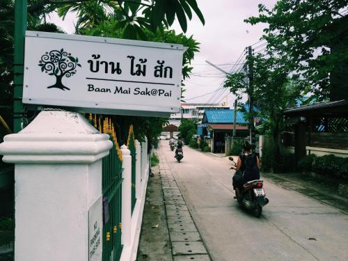 a sign for a bar with people riding motorcycles down a street at Baan Mai Sak in Pai