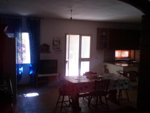 a dining room with a table and two windows at Appartamento MareMontagna in Cardedu