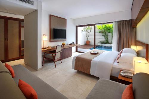 a hotel room with a large bed and a desk at The Magani Hotel and Spa in Legian
