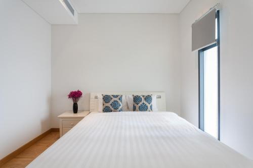 a bedroom with a white bed and a window at The Ocean Apartment IDCWH B602 in Danang