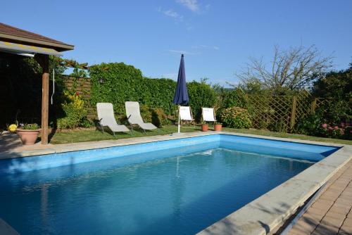 a swimming pool with two chairs and an umbrella at Reiterbauernhof Schönlehenhof in Mank