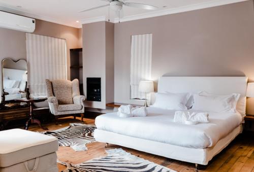 a bedroom with a large white bed and a desk at Edenbrook Country Manor in Plettenberg Bay