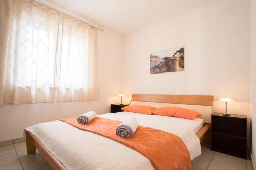 a bedroom with two beds with orange pillows and a window at Apartment Smuljic in Vrboska